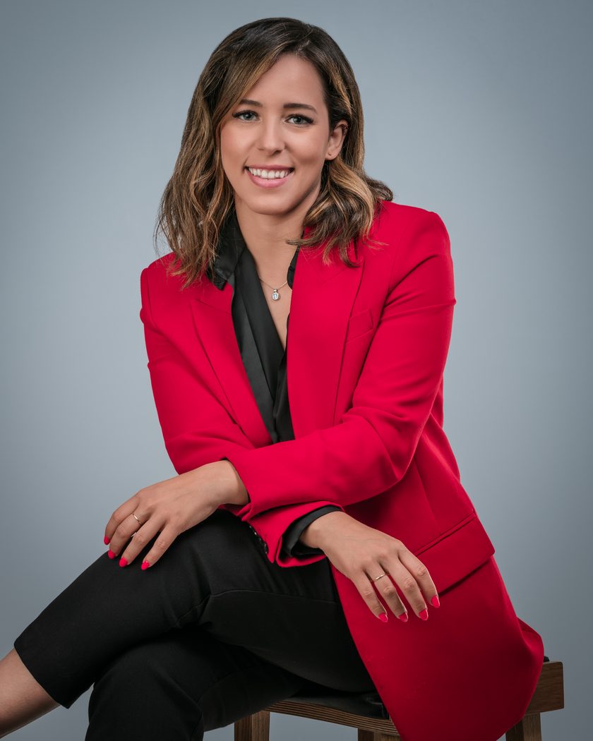 Vicky Baneira, smiling, in a red blazer